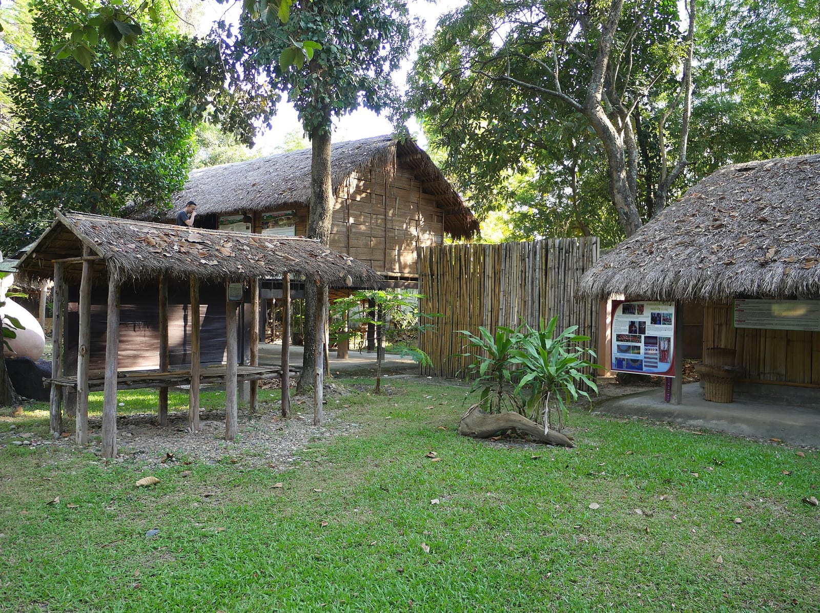 Reconstructed Lisu houses with thatched roofs and a small raised store hut in the museum's open-air village section